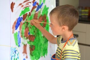 Kind malt selbstvergessen auf Leinwand